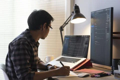Side view of male programmer writing program code on  computer in the home .. Photos