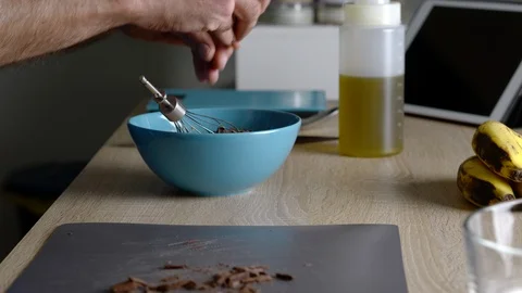 Side view of man adding small pieces of chocolate to the mixture to make some Stock Footage 128825253