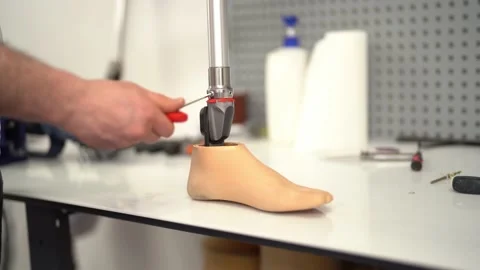Side view of a man assembling prosthetic foot with screwdriver Stock Footage 236621959