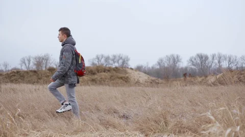 Side view of man with backpack walking along grass in field Stock Footage 128567962