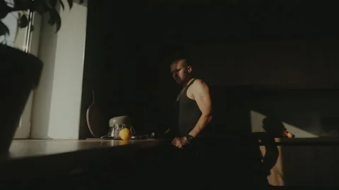 Side view of a man in black t-shirt walking around the kitchen and thinking Stock Footage 251667420