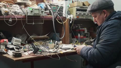 Side view of man in cap sitting at the table. Busy person in his workshop. Stock Footage 151512628