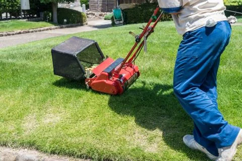 Side view of man cutting grass with lawn mover Stock Photos
