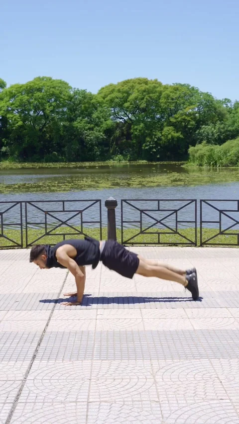 Side view of a man doing burpees in an urban park on a sunny day Video stock 316846481