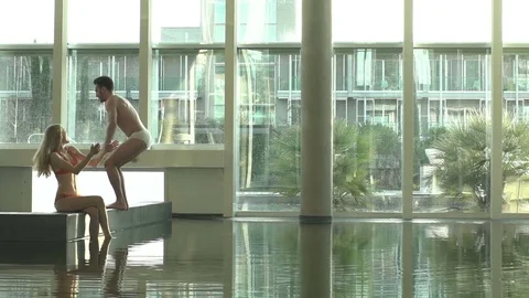 The side view of the man doing the somersault into the pool while his attractive Stock Footage 82616009