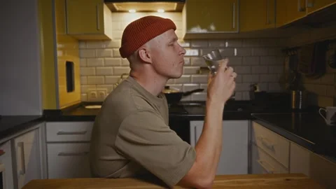 Side view of man drinking water at kitchen table for wellness Stock-Footage 320137723