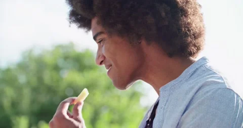 Side view of man eating finger food appetizer and smiling at sunset warm light 動画素材 135335129
