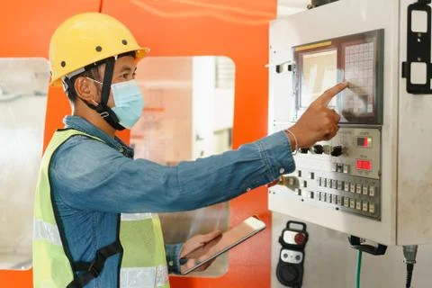 Side view of man engineer  working on machine control panel display Stock Photos