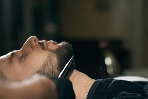Side view of man getting trendy beard in modern barbershop Stock Photos