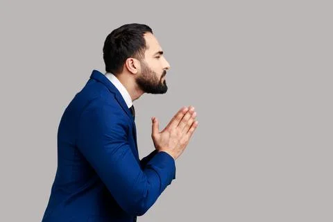 Side view of man holding hands in prayer, looking with imploring pleading Foto stock