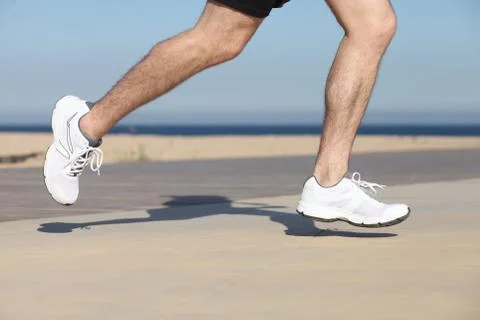 Side view of a man legs running on the concrete of a seafront Stock Photos