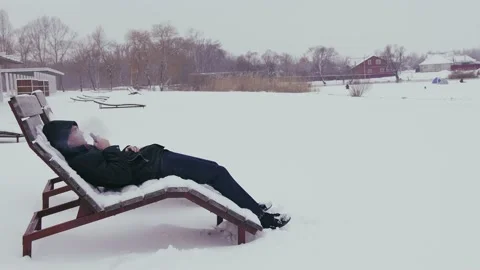 Side view of man lying on sunbed with snow and vaping. Relaxed male lets off Stock Footage 169186350
