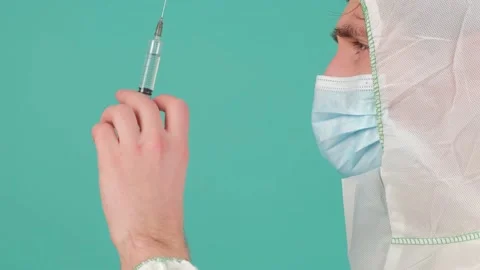 Side view of a man in protective suit staying holding a syringe with vaccine. Stock Footage 156049026