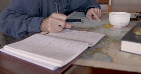 Side view of man researching places to travel to using map and notebook Stock Footage 81476304