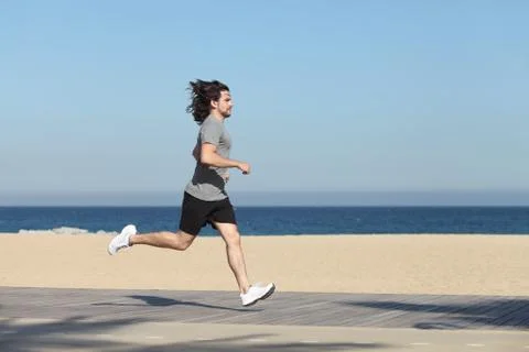 Side view of a man running on the seafront of the beach Stock Photos