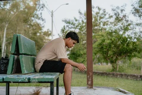 Side view of man sitting on a bench in a thoughtful moment Stock Photos