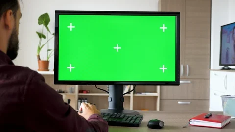 Side view of man sitting in front of computer with big green screen mock-up Stock Footage 95681845