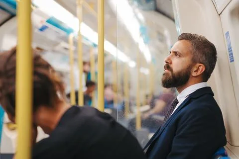 Side view of man sitting in subway train, travelling to work. Stock Photos