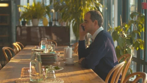 Side view, man talks on the phone in cafe Stock Footage 120723614
