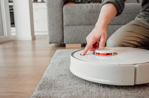 Side view on man turning on robot vacuum cleaner. smart home concept,copy space Stock Photos