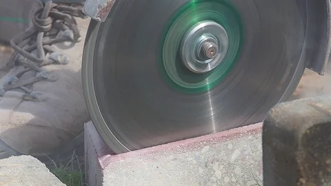 Side view of a man using an angle grinder or circular saw outdoors to cut throug Stock Footage 113418444