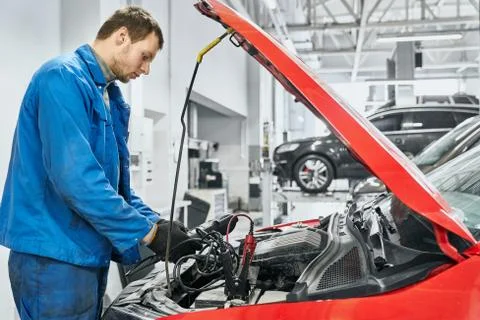 Side view of man using battery jumper cables for chargers Stock Photos