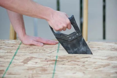 Side view of a man using a hand saw Stock Photos