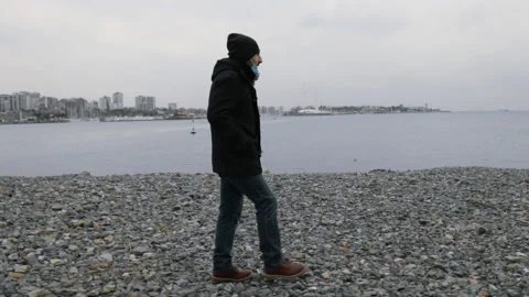 Side view of a man walking alone in slow motion at the beach in winter Stock Footage 144326581
