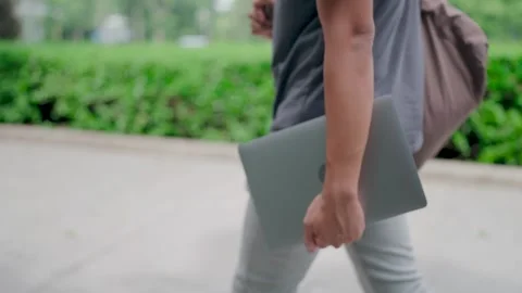 Side view Man walking with laptop and bag in the park, working online Video stock 283186768