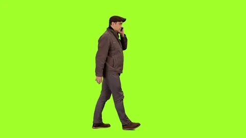 Side view of a man walks and talking on mobile phone on green screen background Stock Footage 71757763