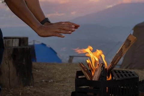 Side view of man warming his hands up on camp fire in winter Stock Photos