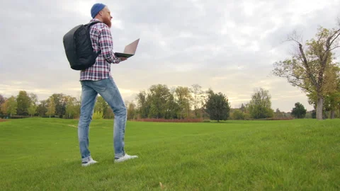 Side view of man wearing backpack, holding laptop, observing unfamiliar area Stock Footage 255332623