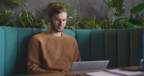 Side view of man who sits in cafe in daytime and using the laptop for the remote Stock Footage 164491657