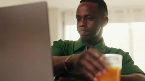 Side view of the Man Working From Home on Laptop With Orange Juice Stock Footage 313552040