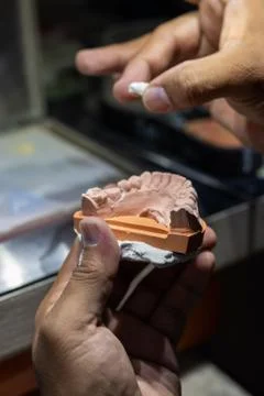 Side view of a man working in a prosthetic tooth, removing the piece from the Stock Photos