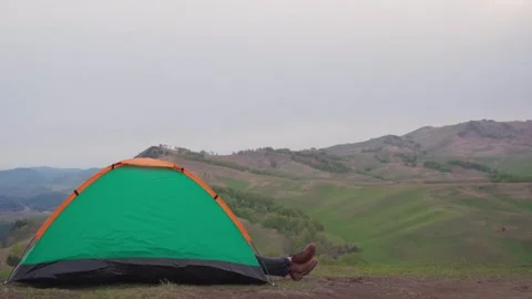 Side view a man's booted feet stick out of a tent. 库存影片 315588508