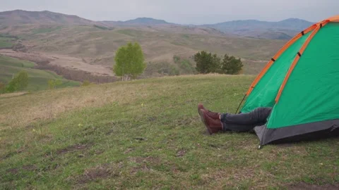 Side view a man's booted feet stick out of a tent. Stock Footage 316512191