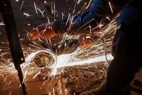 Side view of a man's hands working on a metal part of a garden bench, using a Foto stock