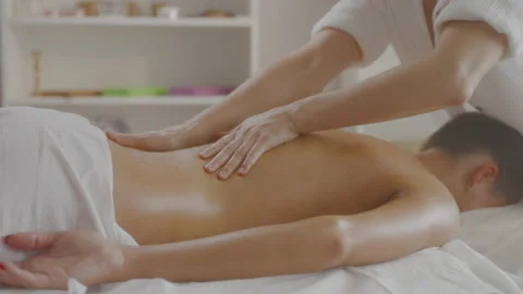 Side view of masseur massaging lumbar back young woman lying on massage table. Stock Footage 197659401
