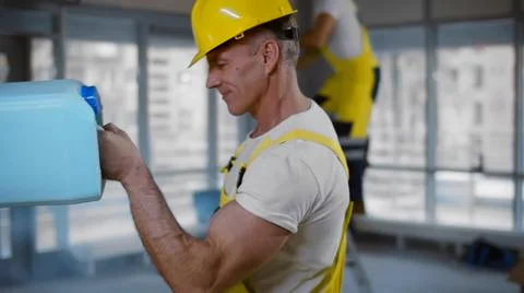 Side view of mature builder using can with construction materials for working Fotos de archivo