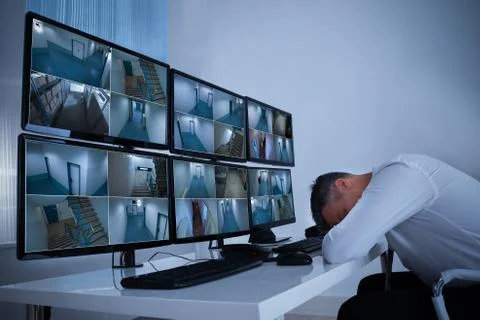 Side view of mature male operator sleeping while leaning on security monitor' Foto stock