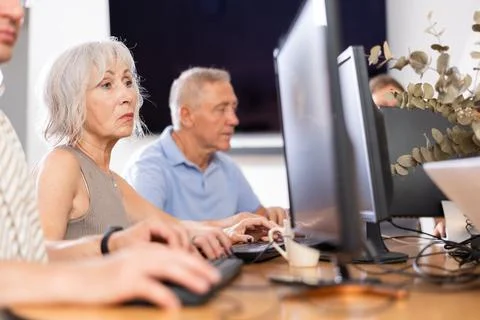Side view of mature people while studying in computer class in nursing home Stock Photos