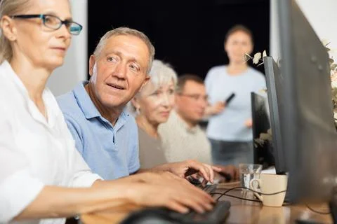 Side view of mature people while studying in computer class in nursing home Stock Photos