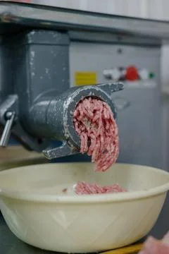 Side view of a meat grinder and minced meat falling into a bowl. Stock Photos