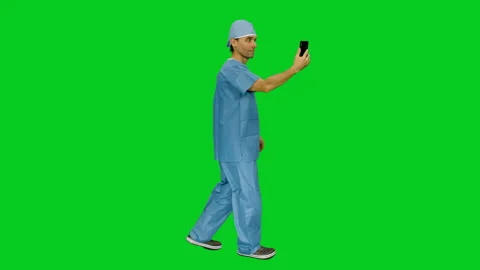 Side view of medic in uniform having a videochat while walking on green screen Video stock 124846421