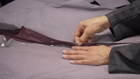 Side view-merchandiser unbuttoning a luxury businessman burgundy dress shirt Stock Footage 96292295