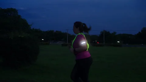 Side view of a middle-aged Asian woman jogging at twilight Stock Footage 335759696