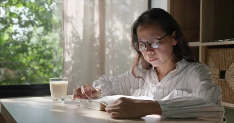 Side view. Middle Aged Asian Woman with Glasses Reading Book in Living Room Видео 338168507