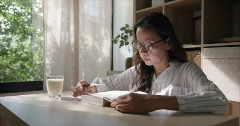 Side view. Middle Aged Asian Woman with Glasses Reading Book in Living Room Stockbeeldmateriaal 338168536