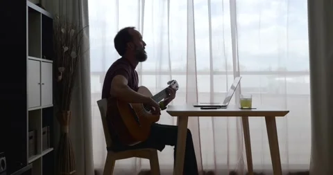 Side view of middle-aged man with beard playing guitar moving to the beat in Stock Footage 160401212